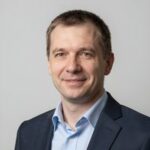 Портрет уверенного российского предпринимателя с дружелюбным взглядом на размытом нейтральном фоне в студии